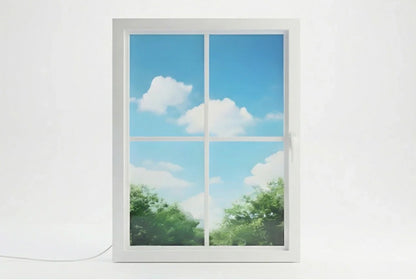 Vindow smart virtual window, white frame, showing blue sky, clouds, and greenery indoors